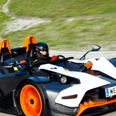 Kierowca w kasku ściga się ekstremalnym KTM X-Bow na torze wyścigowym.