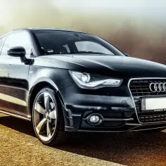 Czarny Audi A1 na drodze. Po zakupie auta warto sprawdzić ubezpieczenie i zarejestrować pojazd.