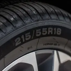 Zbliżenie na oponę z oznaczeniem 215/55R18, wskazującym na oznaczenie opon wielosezonowych.