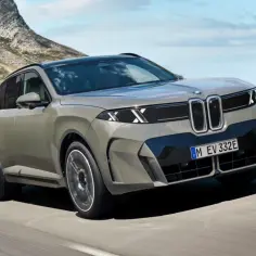 Nowe BMW X5 w kolorze szarym jedzie po malowniczej drodze nad oceanem.
