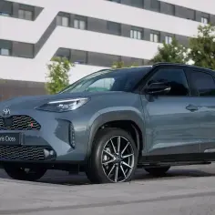 Szary Toyota Yaris Cross GR Sport prezentuje się dynamicznie na tle nowoczesnego budynku.