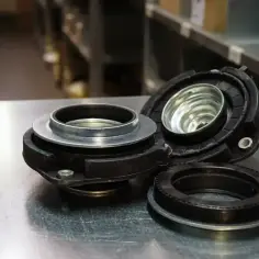 Elementy zawieszenia, w tym łożysko McPhersona, leżą na metalowym blacie.