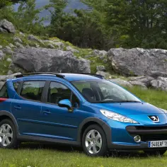 Niebieski Peugeot 207 1.6 HDi na tle skalistego krajobrazu.