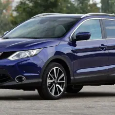 Nowy Nissan Qashqai w kolorze głębokiego granatu, zaparkowany na zewnątrz. Elegancki design i sportowe felgi podkreślają jego nowoczesny charakter.