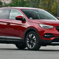 Czerwony Opel Grandland X na drodze. Kierowca w środku, ciekawe opel grandland x opinie.