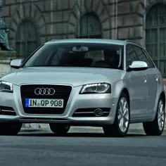Srebrne Audi 8P Sportback z przyciemnianymi szybami i felgami, zaparkowane przed zabytkową kamienicą.