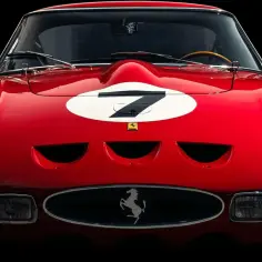 Czerwone Ferrari 250 GTO z numerem 7 na masce, z włączonymi światłami, gotowe do wyścigu.