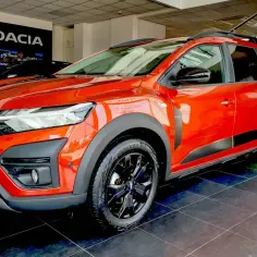 Pomarańczowy Dacia Jogger w salonie. Wiele osób szuka dacia jogger opinie, ten model oferuje 7 miejsc.
