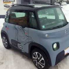 Szary Citroen Ami z mapą terenu na boku, zaparkowany na śniegu. Sprawdź, jaka jest aktualna citroen ami cena!