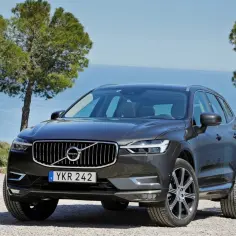 Szary Volvo XC60 na tle morza i drzew. Wiele pozytywnych volvo xc60 opinie potwierdza jego jakość.