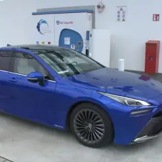 Niebieska Toyota Mirai na stacji wodorowej. Zastanawiasz się nad toyota mirai cena?