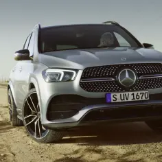 Srebrny Mercedes GLE 300d na pustynnej drodze. Za kierownicą siedzi kobieta.
