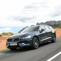 Ciemnoszary Volvo V60 na drodze, krajobraz górski w tle. Wiele pozytywnych volvo v60 opinie potwierdza jego styl i komfort.