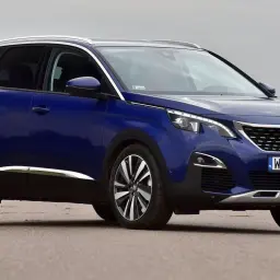 Niebieski Peugeot 3008 na drodze, z widocznym grillem i tablicą rejestracyjną.