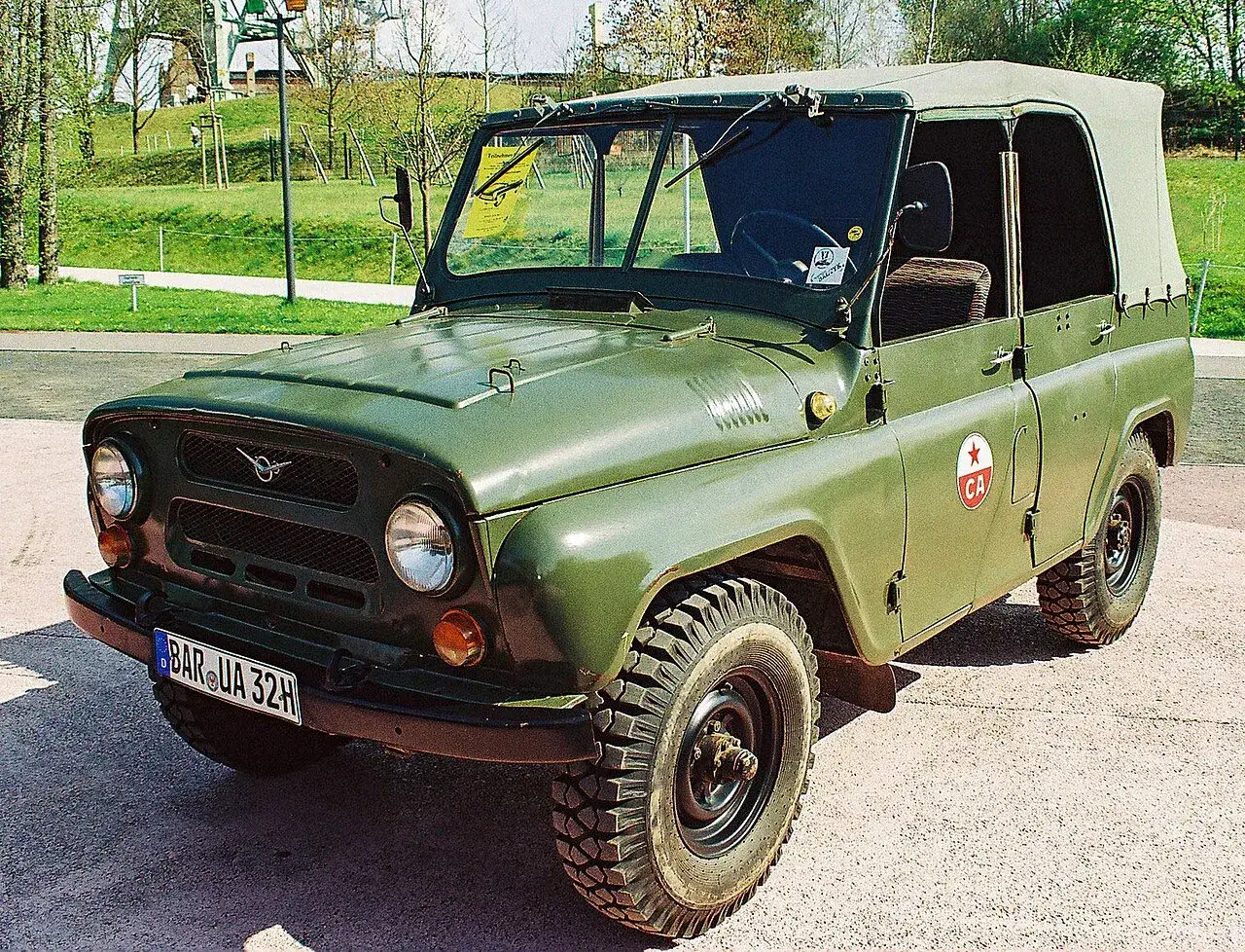 Zielony UAZ, marka samochodu na u, z charakterystycznym emblematem i plandeką, gotowy na terenowe wyzwania.