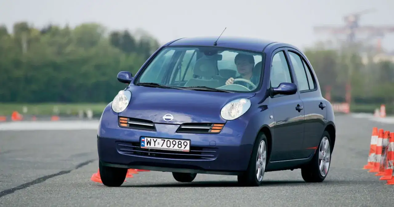 Niebieski Nissan Micra K12 manewruje między pachołkami na torze.
