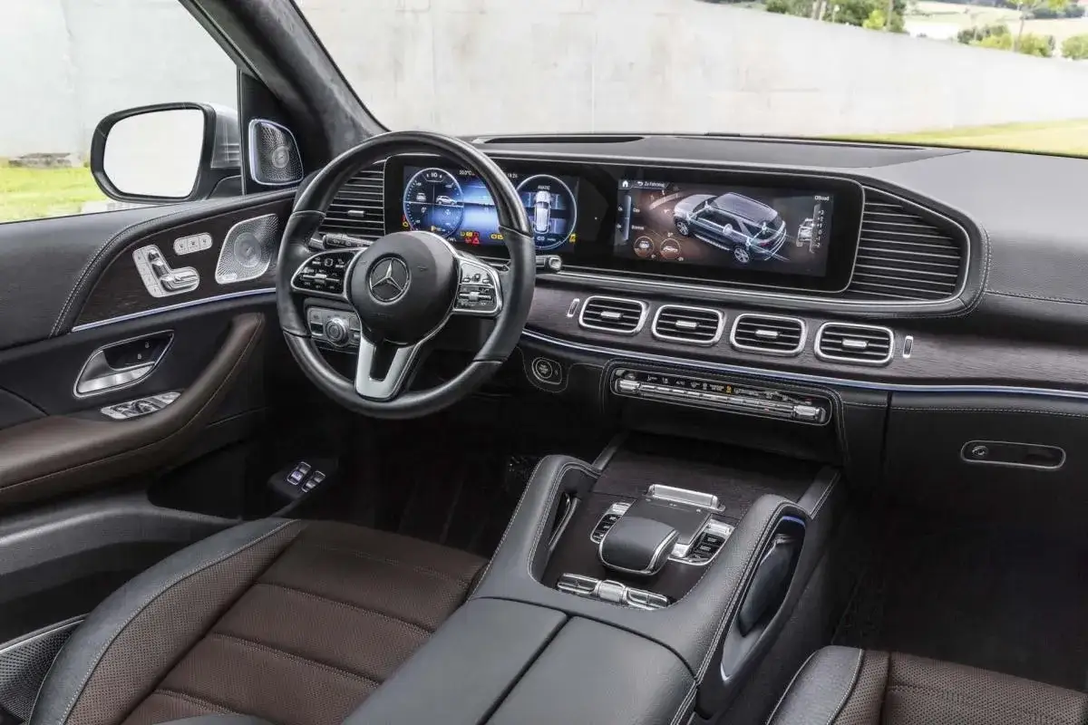 Wnętrze luksusowego Mercedesa GLE 300d z nowoczesnym panelem cyfrowym, skórzaną tapicerką i drewnianymi wstawkami.