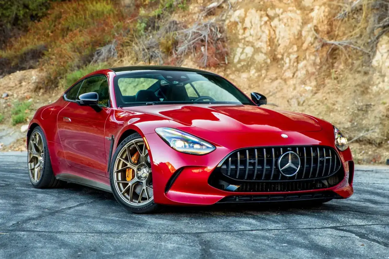 Czerwony Mercedes GT 63 z brązowymi felgami na tle skalistego zbocza.