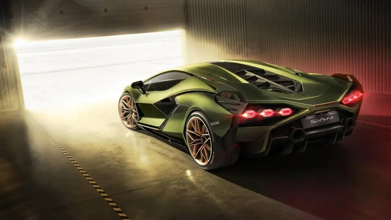 Zielony Lamborghini Sian z miedzianymi felgami wychodzi z garażu, oświetlony słońcem.