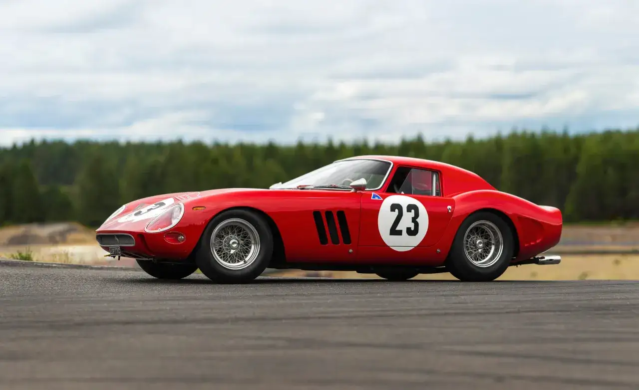 Klasyczny czerwony Ferrari 250 GTO z numerem 23 na białym kółku, gotowy do wyścigu na torze.