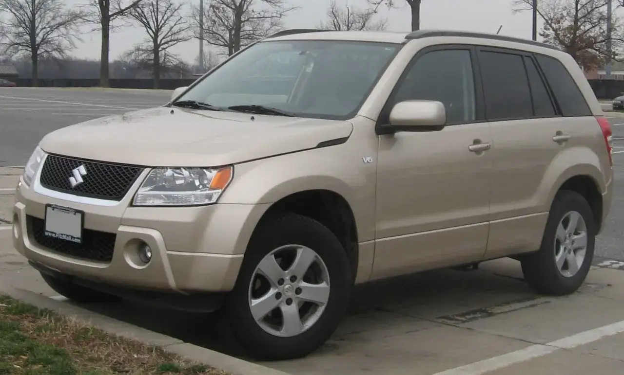 Złoty Suzuki Grand Vitara 2, SUV z napędem V6, zaparkowany przy krawężniku.