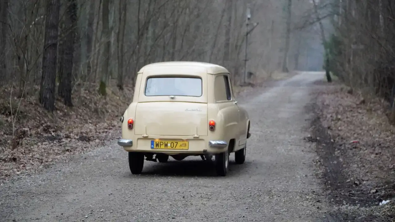 Beżowy Peugeot 404 w wersji dostawczej jedzie leśną drogą.