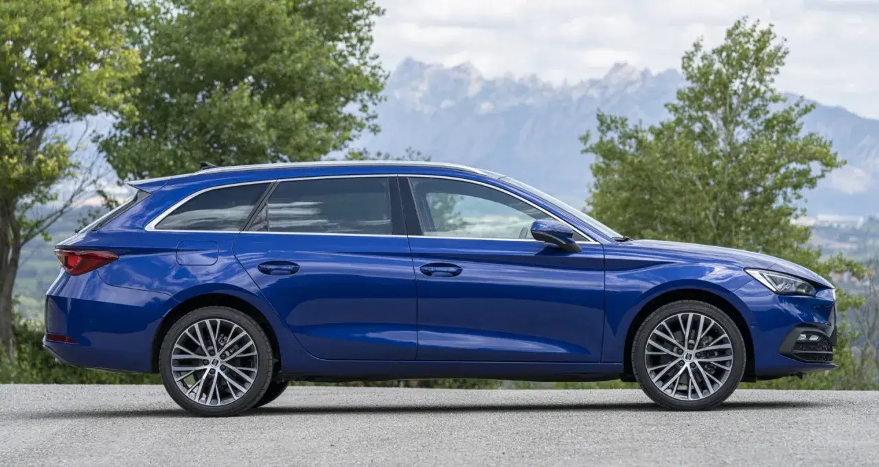 Niebieski Seat Leon 4 kombi na tle gór i drzew.