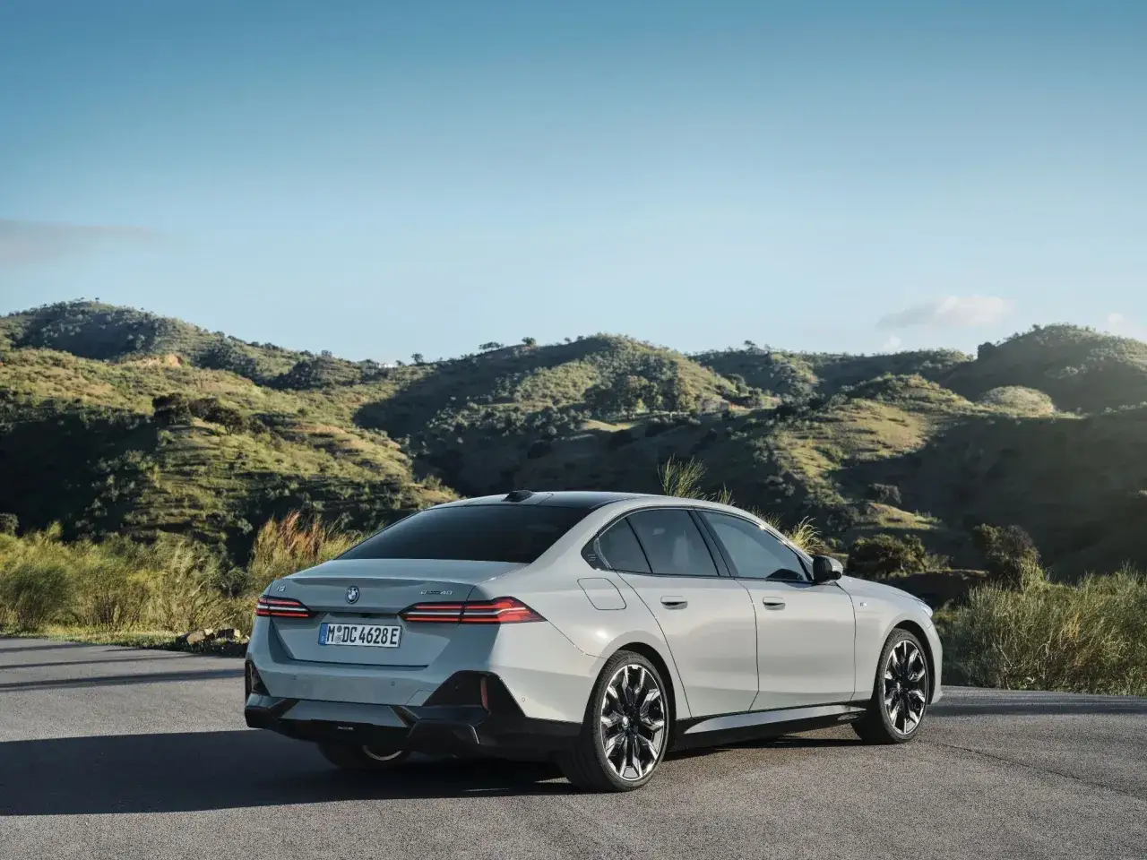Nowe BMW 5 na tle malowniczych wzgórz. Elegancka sylwetka i nowoczesne detale podkreślają jego prestiż.