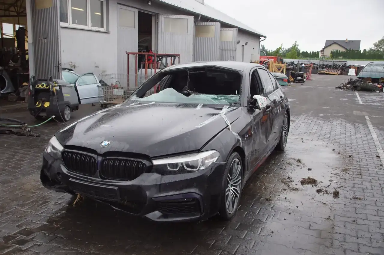 Uszkodzone BMW 520d xdrive na placu złomowiska. Zniszczona przednia szyba i maska.