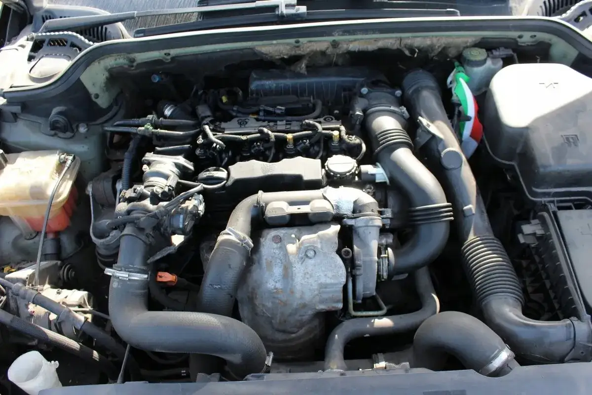 Silnik Peugeot 207 1.6 HDi z widocznymi przewodami, turbosprężarką i zbiorniczkiem płynu.
