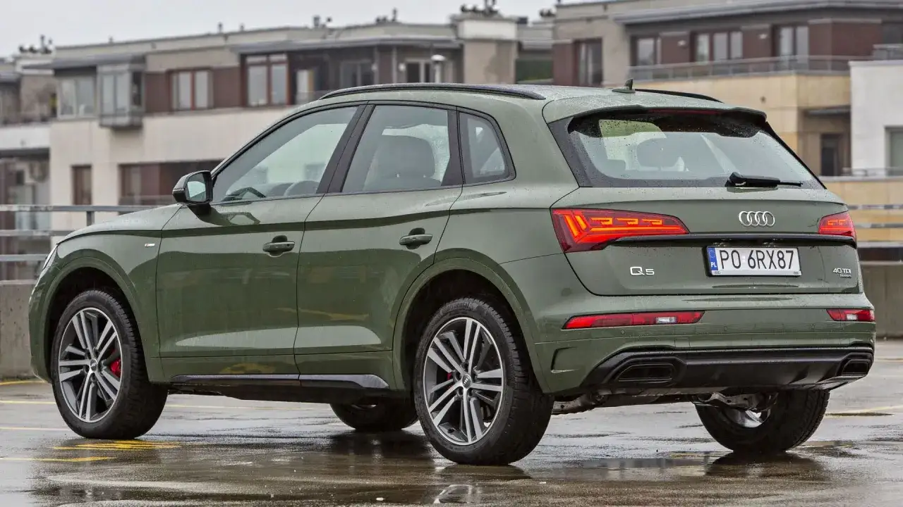 Zielone Audi Q5 na mokrym parkingu. Sprawdź audi q5 wymiary, by poznać jego gabaryty.