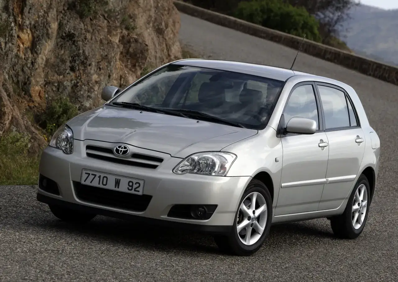 Srebrna Toyota Corolla E12 na krętej drodze, z kamienistym zboczem w tle.