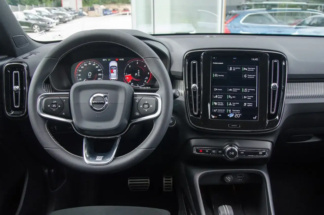 Wnętrze Volvo XC60, kierownica i ekran multimedialny. Wiele osób szuka volvo xc60 opinie, a ten widok pokazuje nowoczesne rozwiązania.