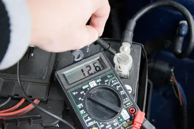 Pomiar napięcia akumulatora multimetrem pokazuje 12.6V.