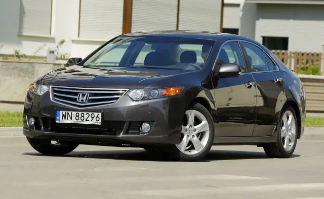 Ciemnoszary sedan Honda Accord z polskimi tablicami rejestracyjnymi WN 88296, zaparkowany przed budynkiem.